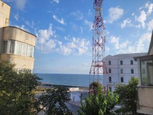 una torre de comunicación junto a un edificio y el océano en Neversea Suite en Constanza