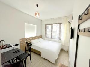 ein kleines Schlafzimmer mit einem weißen Bett und einem Schreibtisch in der Unterkunft Menesa Hotel in Istanbul
