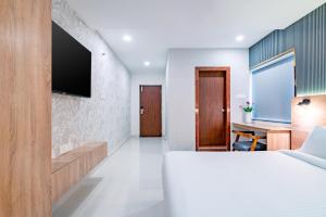 1 dormitorio con 1 cama y TV en la pared en Harvey's Hotels (Gachibowli), en Hyderabad