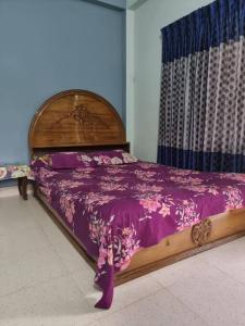 a bedroom with a wooden bed with a purple bedspread at Syed monjil 