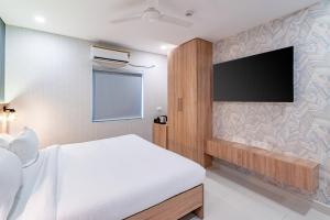 a bedroom with a bed and a flat screen tv at Harvey's Hotels (Gachibowli) in Hyderabad