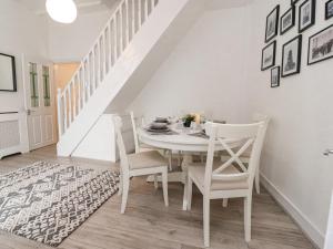 a white dining room with a white table and chairs at Kitty Cottage in Blackpool