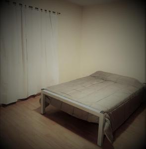 uma cama num quarto com uma parede branca em Departamento en Capital Mendoza 1 ubicadisimo estacionamiento incluido em Mendoza