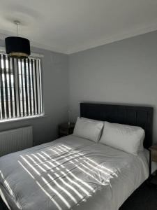 a bedroom with a bed with white sheets and a window at Kenton Apartment- Wembley links in Harrow Weald