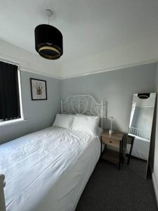 a bedroom with a white bed and a night stand at Kenton Apartment- Wembley links in Harrow Weald