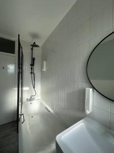 La salle de bains est pourvue d'une baignoire, d'un lavabo et d'un miroir. dans l'établissement Kenton Apartment- Wembley links, à Harrow Weald