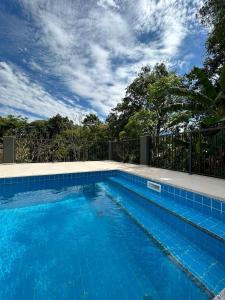 uma piscina com água azul em frente a uma cerca em Hotel Penedo Inn em Penedo