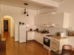 Cozy 2 Bedroom apt @Panormou Metro/Erytros Stavros في أثينا: مطبخ أبيض مع دواليب بيضاء وأرضية خشبية