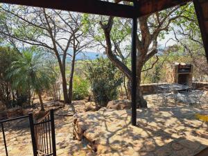 a patio with a table and a grill and trees at Amani Bush Escape in Buffelspoort