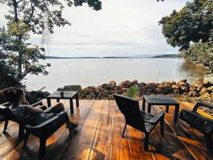 una mujer sentada en una cubierta con vistas a un cuerpo de agua en Mosana Reef Garden B&B en Bocas Town