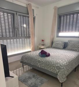 a bedroom with a bed and two windows with shutters at Unique Luxurious New 4BR near Beach in Haifa