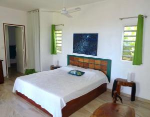 ein Schlafzimmer mit einem Bett und einem Stuhl sowie zwei Fenstern in der Unterkunft Bungalow DOUROU in Deshaies