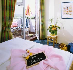 una camera con un cartello di benvenuto su un letto di Hotel Strandburg a Baltrum
