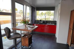 una cocina con armarios rojos y una mesa con flores. en Hafen Perle - Übernachtungen auf dem Wasser- Romantik & Wellness auf dem Rhein -, en Leverkusen