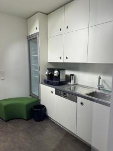 a kitchen with white cabinets and a green ottoman at SleepWell100 in Cologne