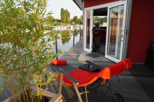 una sedia rossa seduta sul ponte di una casa di Hafen Perle - Übernachtungen auf dem Wasser- Romantik & Wellness auf dem Rhein - a Leverkusen