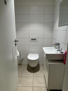 a white bathroom with a toilet and a sink at SleepWell100 in Cologne