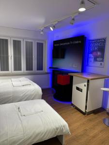 a room with two beds and a table with a monitor at SleepWell100 in Cologne