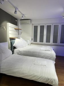 two white beds in a room with windows at SleepWell100 in Cologne
