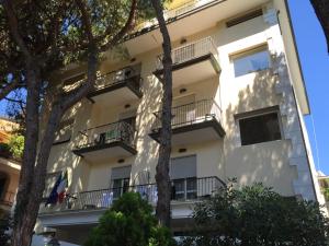 biały apartamentowiec z balkonami i drzewami w obiekcie Hotel Cortina w Rimini