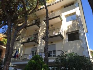 a white apartment building with balconies and trees at Hotel Cortina in Rimini