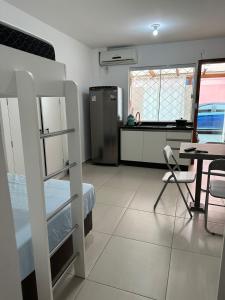 a bedroom with a bunk bed and a table and a kitchen at Apartamento studio térreo in Balneário Camboriú