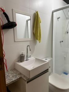 a bathroom with a sink and a toilet and a mirror at Apartamento studio térreo in Balneário Camboriú