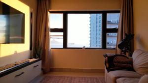 a living room with a couch and a large window at Seacret Whale in Bloubergstrand