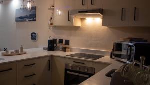 a kitchen with a microwave and a stove top oven at Seacret Whale in Bloubergstrand