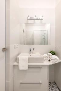 een witte badkamer met een wastafel en een spiegel bij Apartament Paparazzi in Warschau