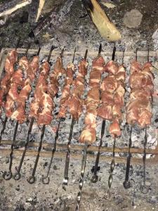 a bunch of meat on a grill with tongs at Chalet Bakhmaro in Chʼkhakoura