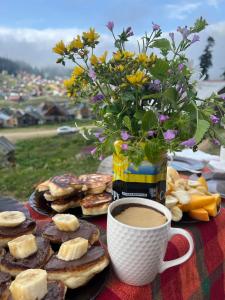 una mesa con una taza de café y un jarrón de flores en Chalet Bakhmaro en Chʼkhakoura