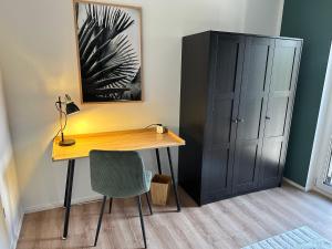 a desk with a chair and a cabinet in a room at Ferienwohnung-Parkplatz-Balkon-Küche-Aufzug-SmartTV-Waschtrockner in Erlangen