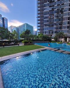 a large swimming pool in a city with tall buildings at Uptown Parksuites Tower 1 BGC - Staycations Up Above 12 Modern 1BR in Manila