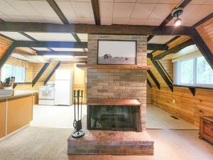 a living room with a brick fireplace with a tv at River's Edge Retreat in Evart