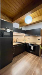 a large kitchen with black cabinets and a sink at Horský apartmán Říčky in Wüstenei