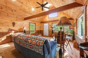 Cabaña de madera con sala de estar con sofá y ventilador de techo. en Wildlife Haven Retreat, en Evart