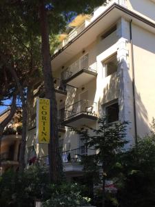 a white building with a sign in front of it at Hotel Cortina in Rimini