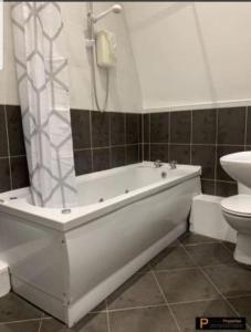 a bathroom with a white tub and a toilet at Make yourself at home! 34AA in Headingley