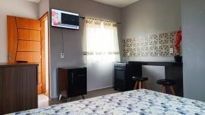 um quarto com uma cama e uma televisão na parede em Hospedagem recanto do sábia flat 01 em Alto Caparaó