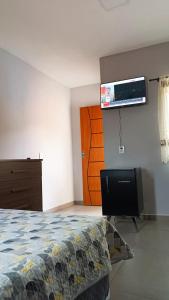 1 dormitorio con 1 cama y TV de pantalla plana en la pared en Hospedagem recanto do sábia flat 01, en Caparaó Velho