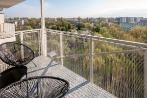 a balcony with two chairs and a view of the city at Manufaktura Business Suites - Parking, Balcony, Nature View, Shopping Nearby, Fast Internet - by Rentujemy in Łódź