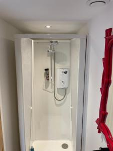 uma cabina de duche na casa de banho com uma cortina vermelha em High spec studio cabin-Farnham centre em Farnham