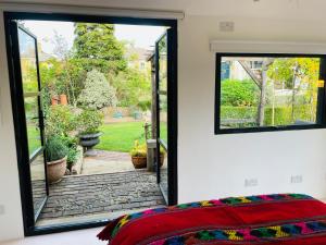 a bedroom with a view of a garden through a window at High spec studio cabin-Farnham centre in Farnham