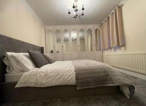 Un dormitorio con una cama grande y una lámpara de araña. en Cheshunt Hertfordshire 4 bed en Cheshunt