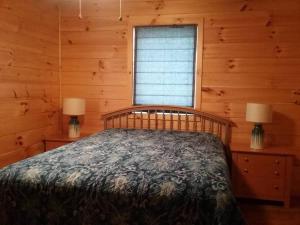 um quarto com uma cama num chalé de madeira em Timber Bend Retreat em Evart