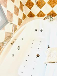 a tub in a bathroom with a tiled wall at Palacio de Miraflores in Miraflores de la Sierra