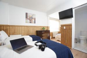 Habitación de hotel con 2 camas, ordenador portátil y cámara en Hostal Hielo Sur en Punta Arenas