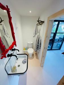 a bathroom with a sink and a toilet and a mirror at High spec studio cabin-Farnham centre in Farnham