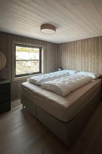 a large bed in a bedroom with a window at Helårs moderne familiehytte med wifi, billader, ski inn, ski ut og utmerket beliggenhet in Drangedal